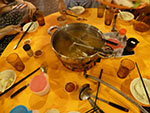 A pot of boiling soup is placed at the center of the table